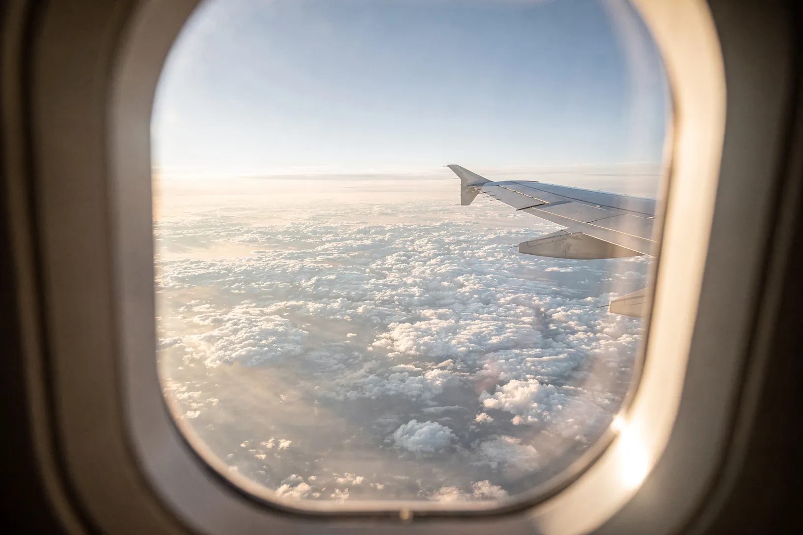 Blick aus dem Flugzeugfenster auf ein ruhiges Wolkenmeer.
