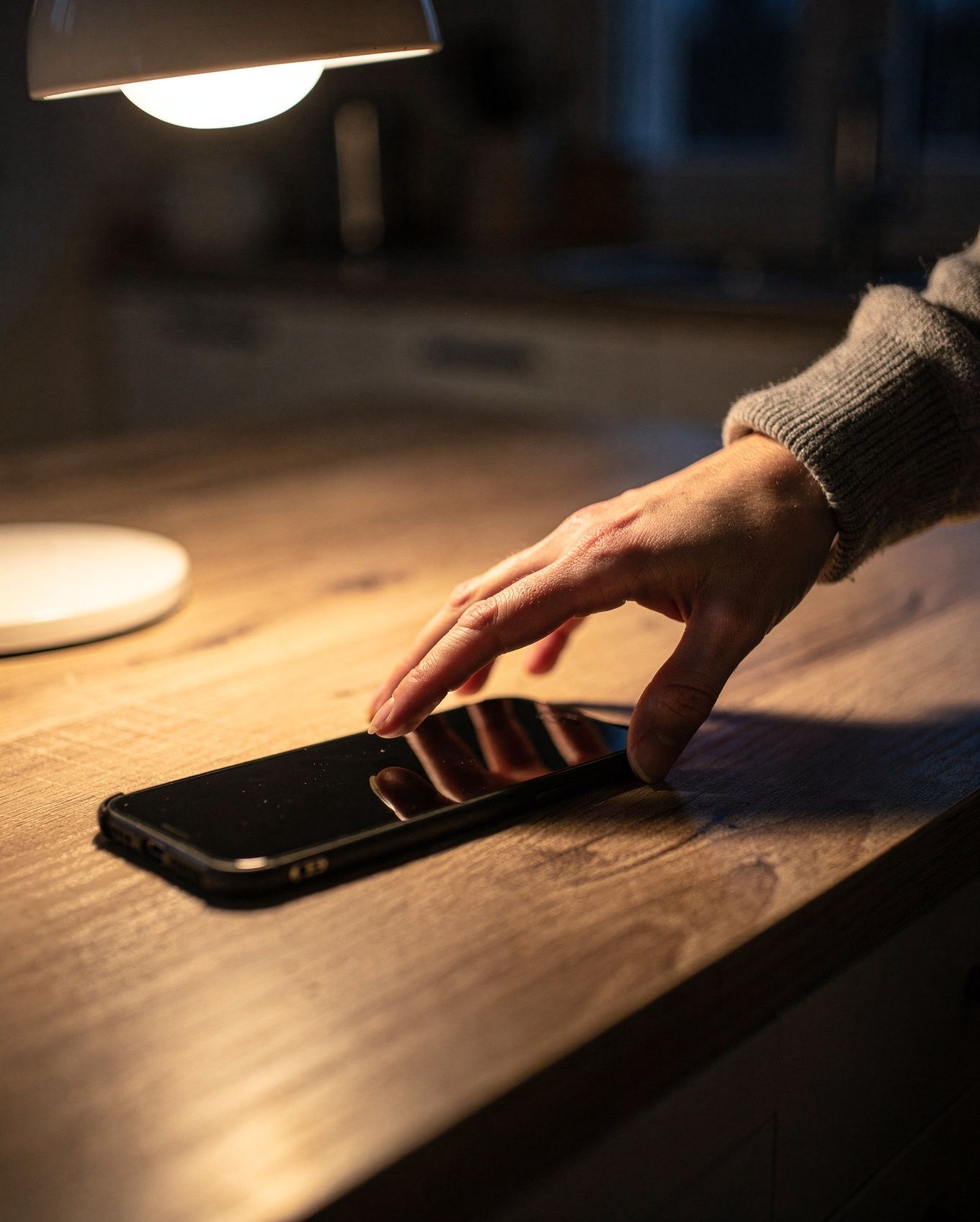 Eine Hand hält kurz inne, bevor sie zum Handy greift.