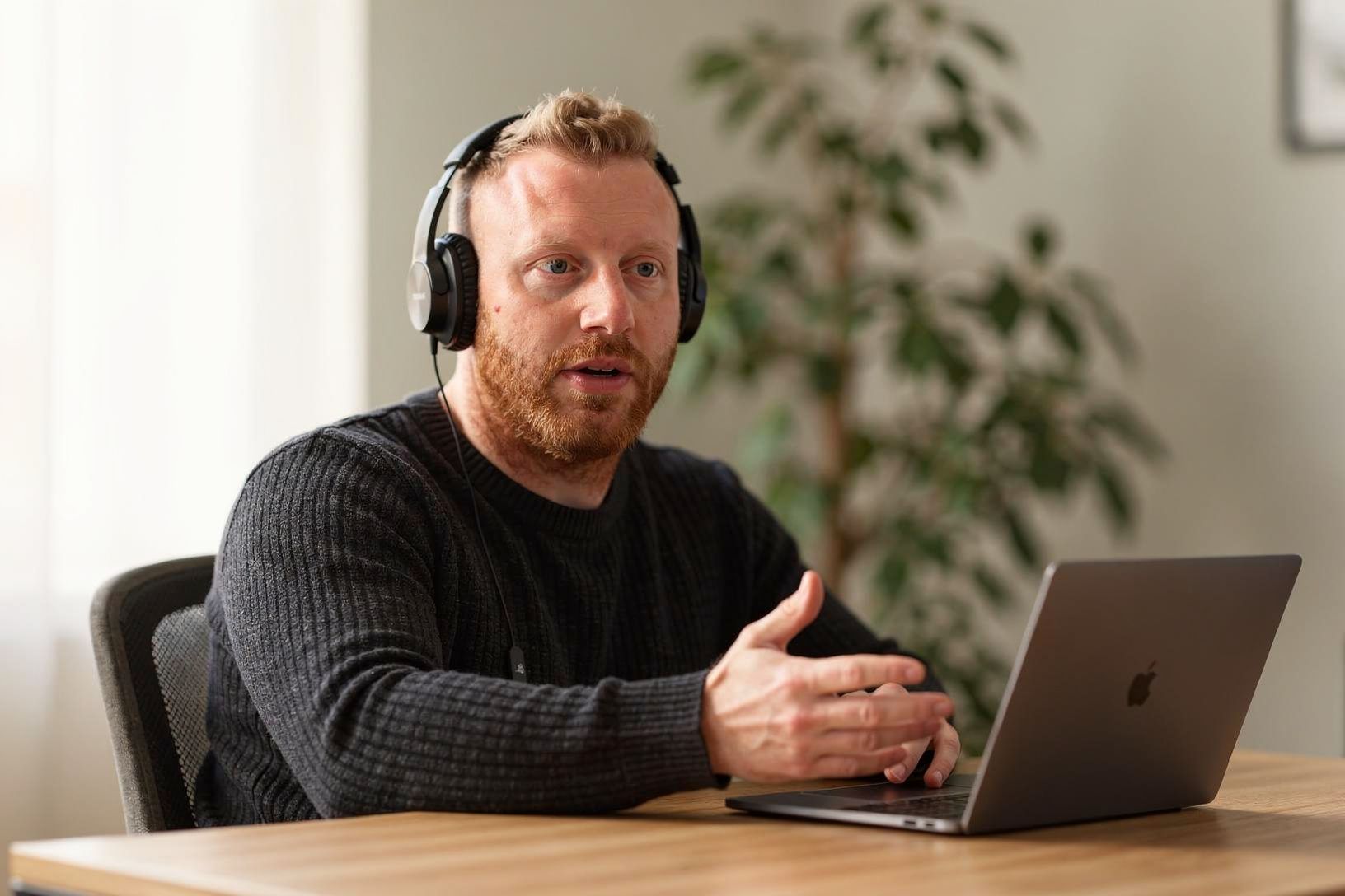Tommy Müller spricht mit Kopfhörern ruhig in einen Videocall.